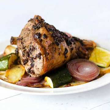 Gigot d'agneau &agrave; la grecque avec oignons, pommes de terre et courgettes