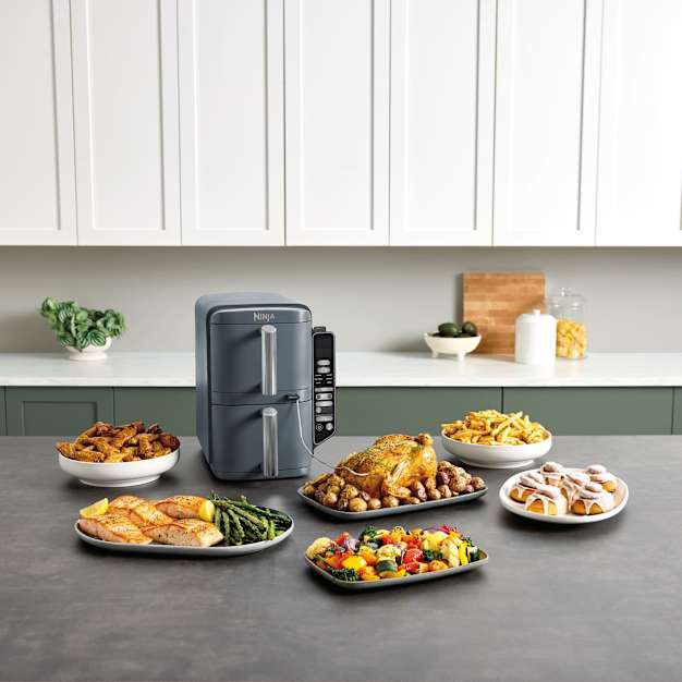 Air fryer Ninja Double Stack entour&eacute; de plats de nourriture.