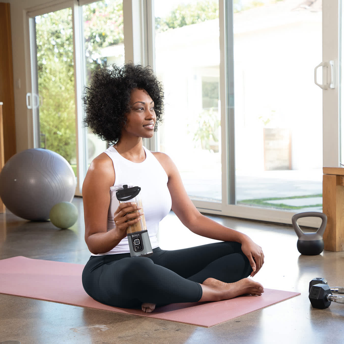 personne buvant depuis le blender portable Ninja sur un tapis de yoga