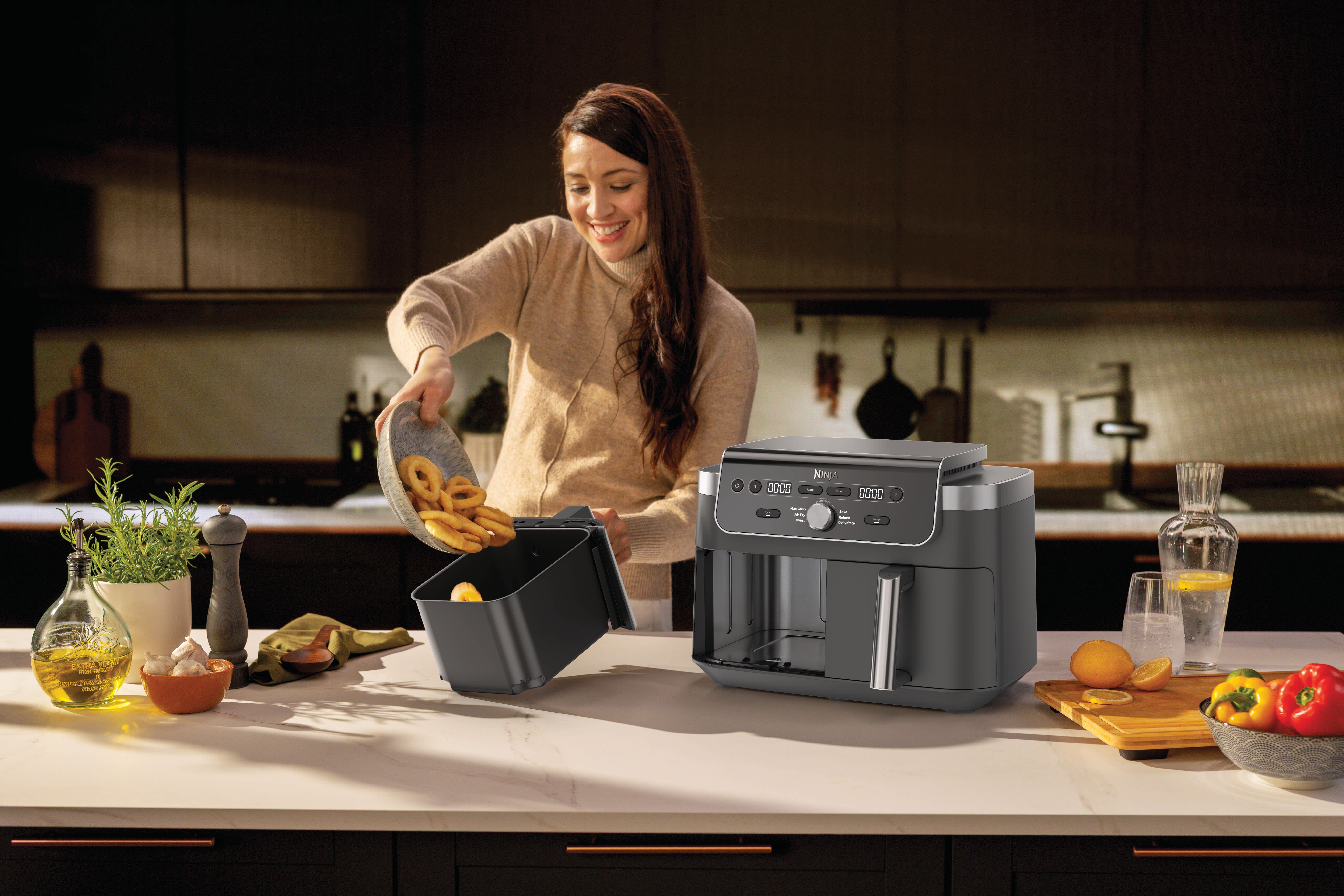 Personne versant des rondelles d'oignon dans l'air fryer.