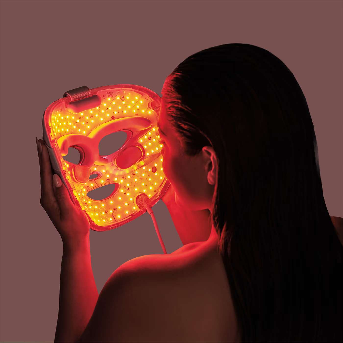 Vanessa putting on red light therapy mask 