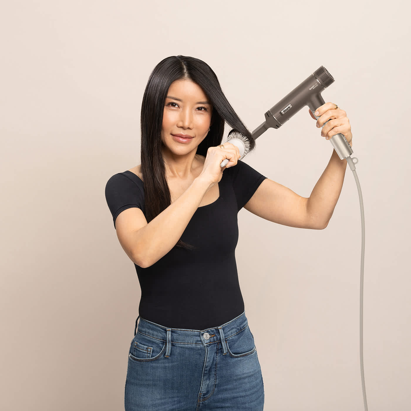 Femme se s&eacute;chant les cheveux avec une brosse et un s&egrave;che-cheveux.