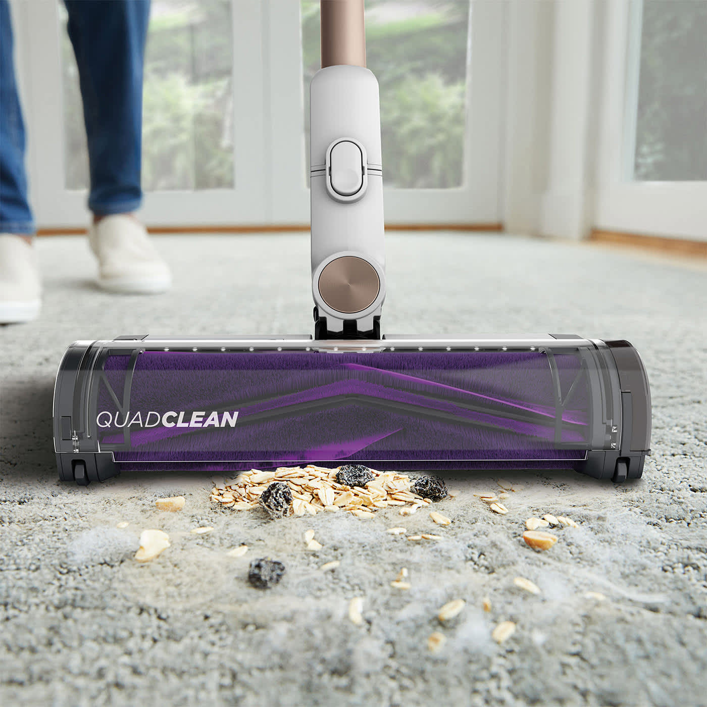 Aspirateur sans fil Shark aspirant des restes de nourriture sur un tapis.