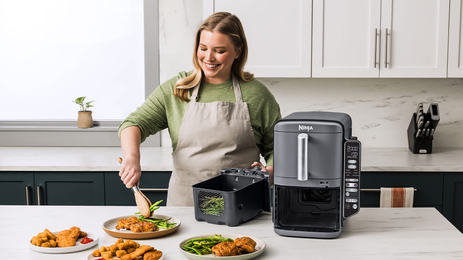 Personne sortant des haricots verts de l'air fryer Ninja et les d&eacute;posant dans une assiette.