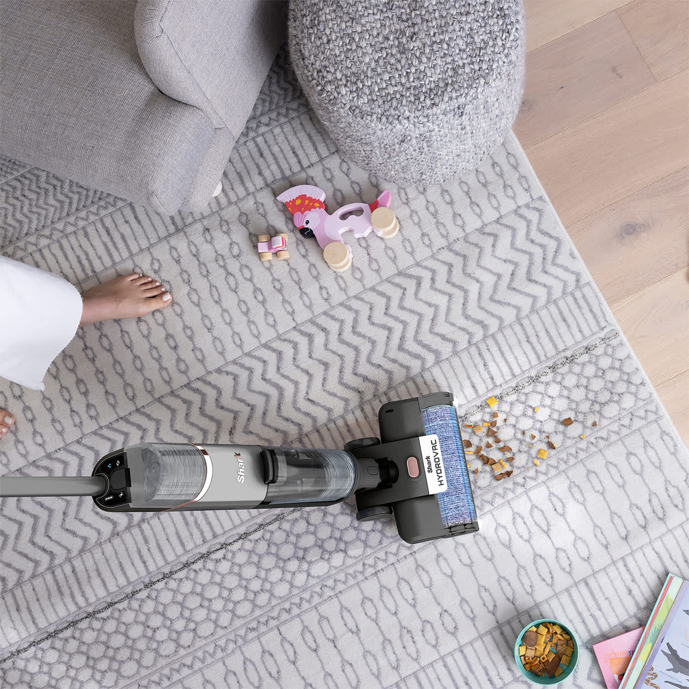 Personne aspirant des miettes d'un tapis avec l'aspirateur Shark.