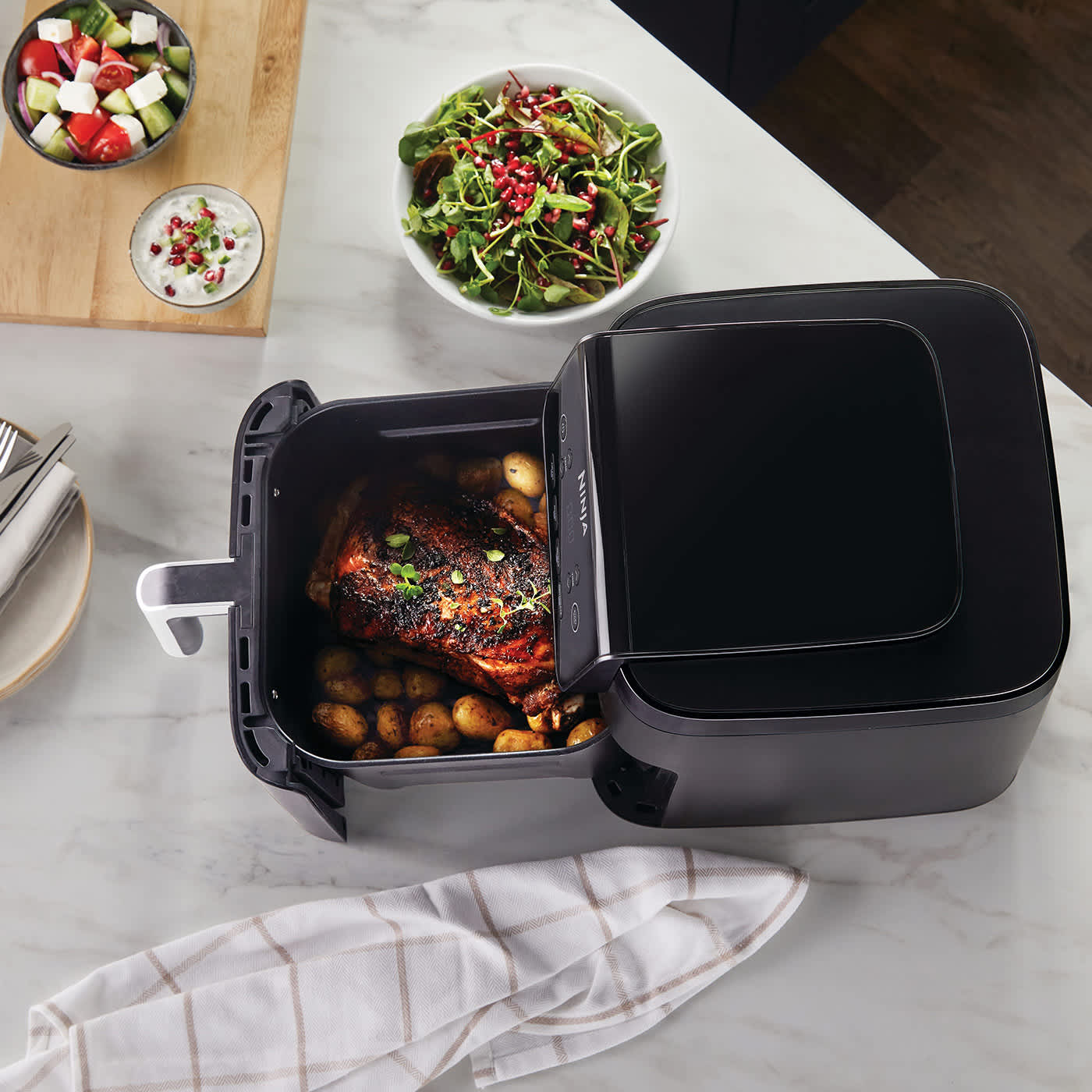 Airfryer avec tiroir ouvert contenant de la viande et des pommes de terre.