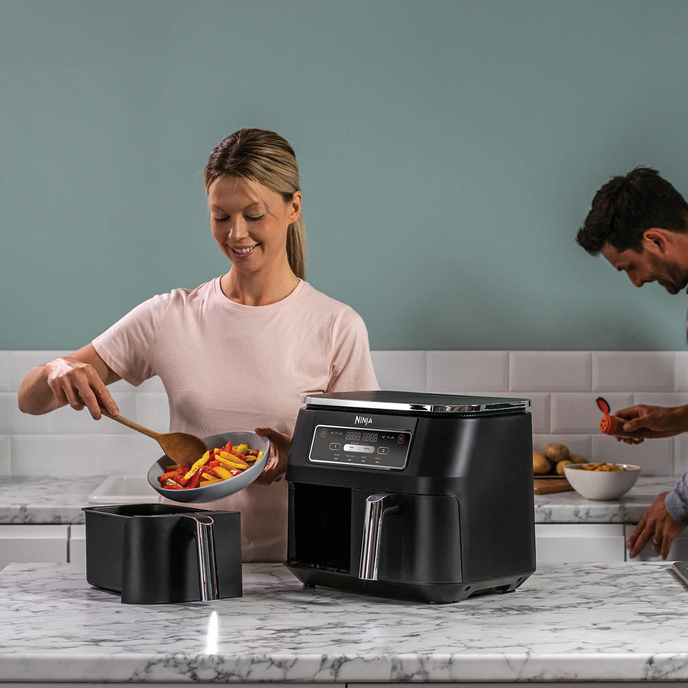 Personne mettant des l&eacute;gumes dans l&rsquo;Airfryer.