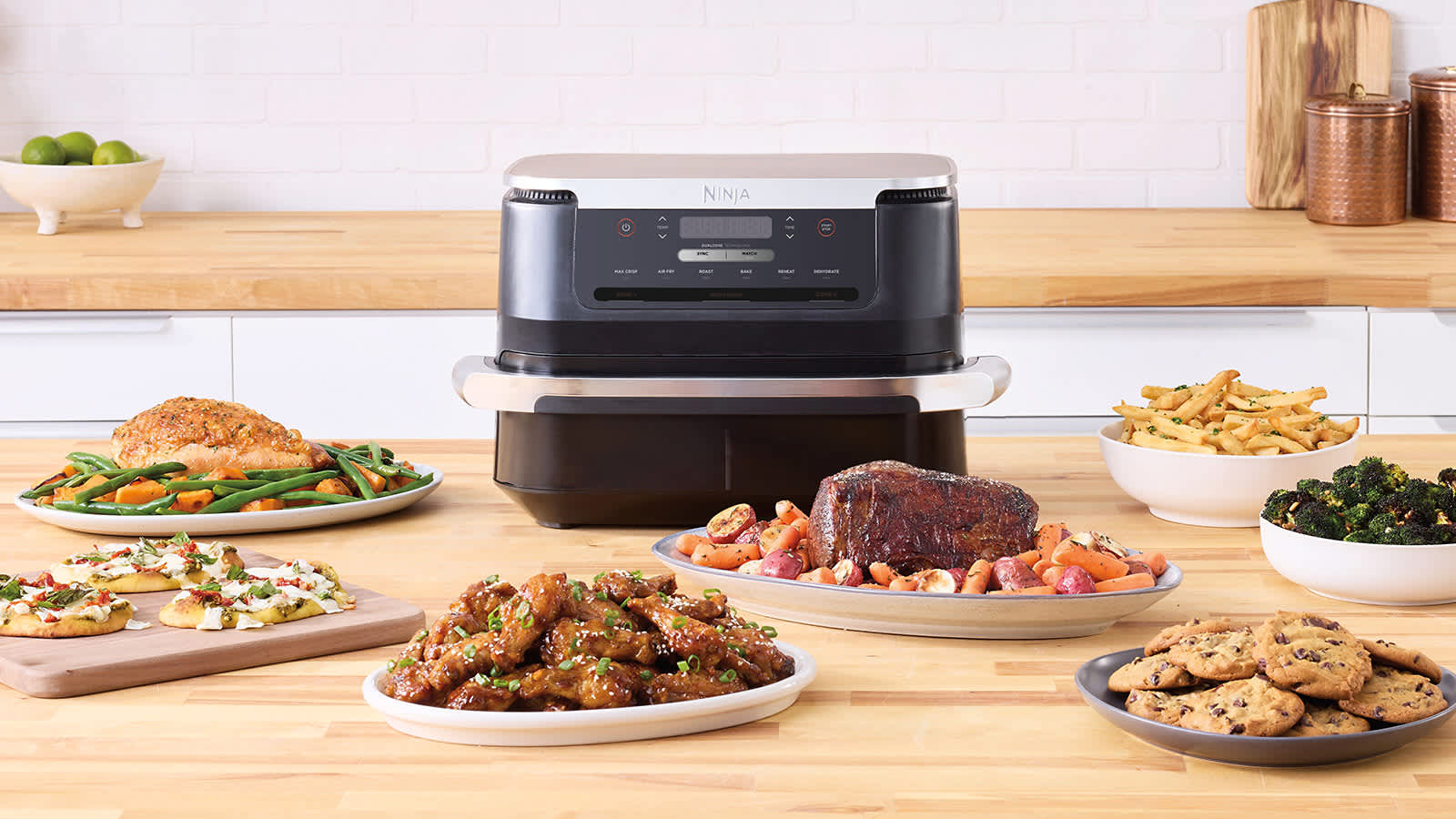 Air fryer sur un comptoir &agrave; c&ocirc;t&eacute; d'assiettes de nourriture.