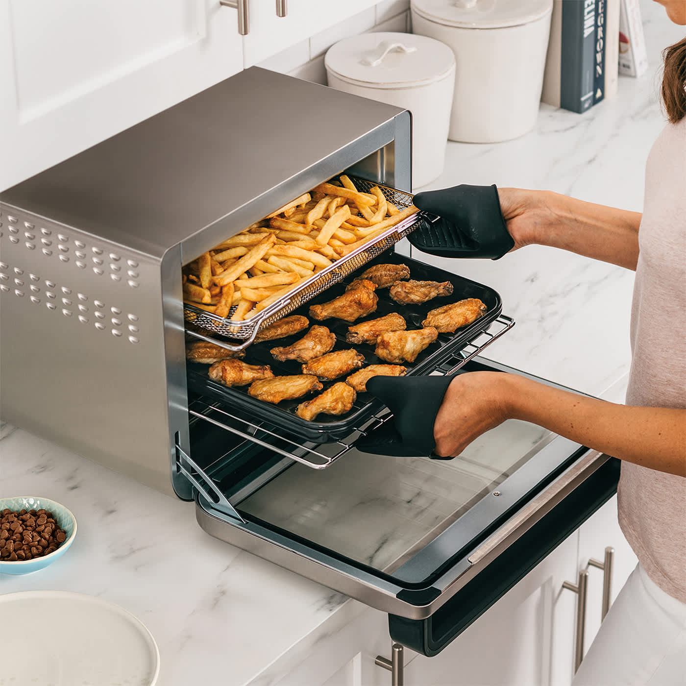Personne cuisinant des ailes de poulet et des frites dans four mini multifonction
