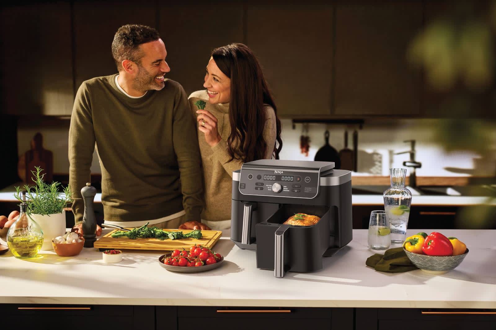 Homme et femme cuisinant avec un Airfryer sur un plan de travail de cuisine.