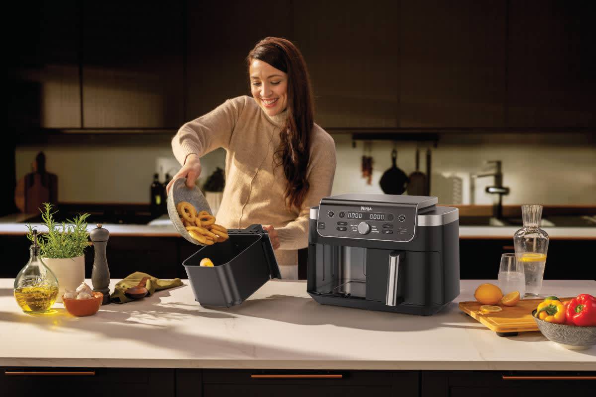 Femme versant des rondelles d&rsquo;oignon dans l&rsquo;Airfryer.