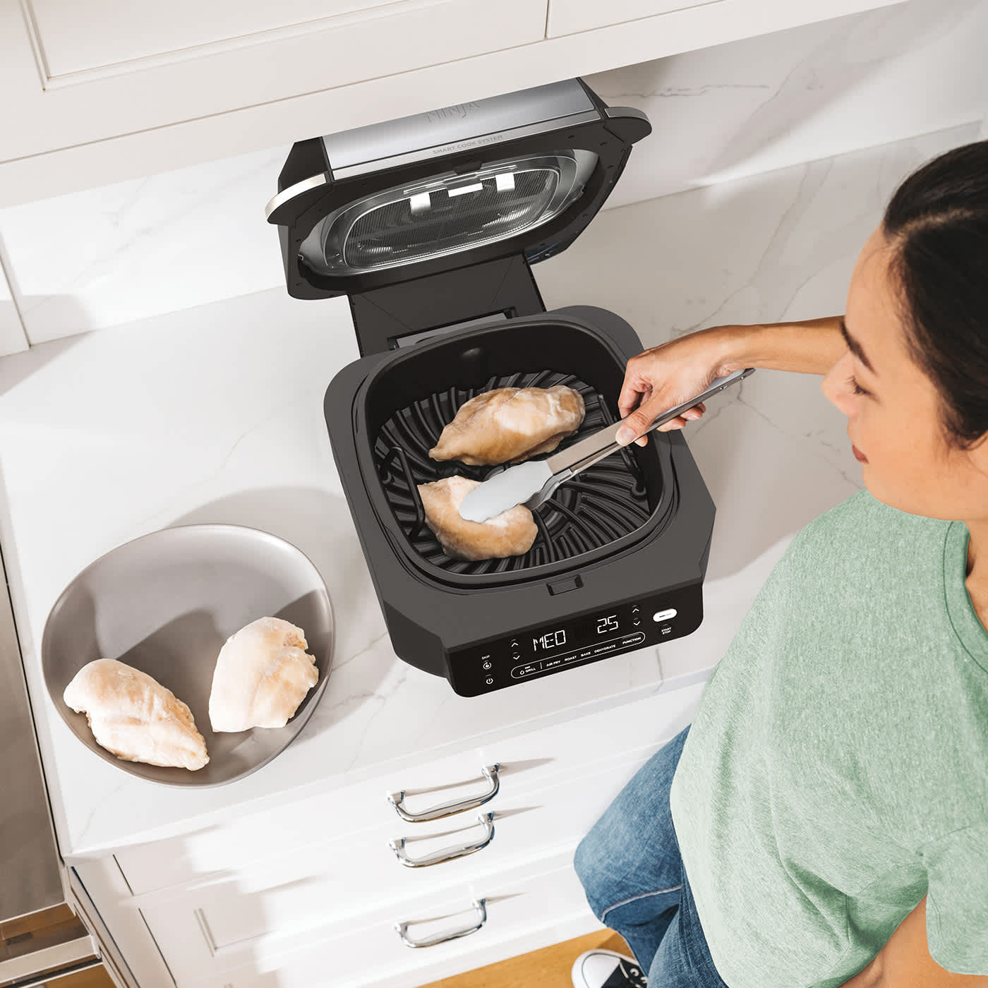 Personne cuisant du poulet avec le grill et l&rsquo;Airfryer Ninja.