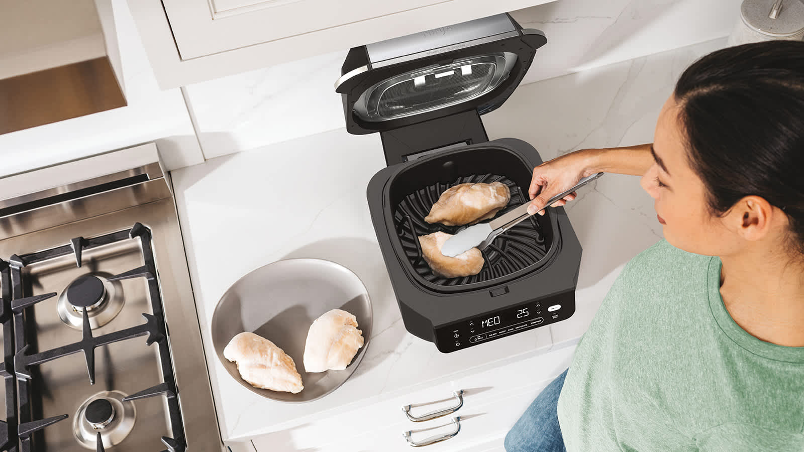Personne cuisant du poulet avec le grill et l&rsquo;Airfryer Ninja.