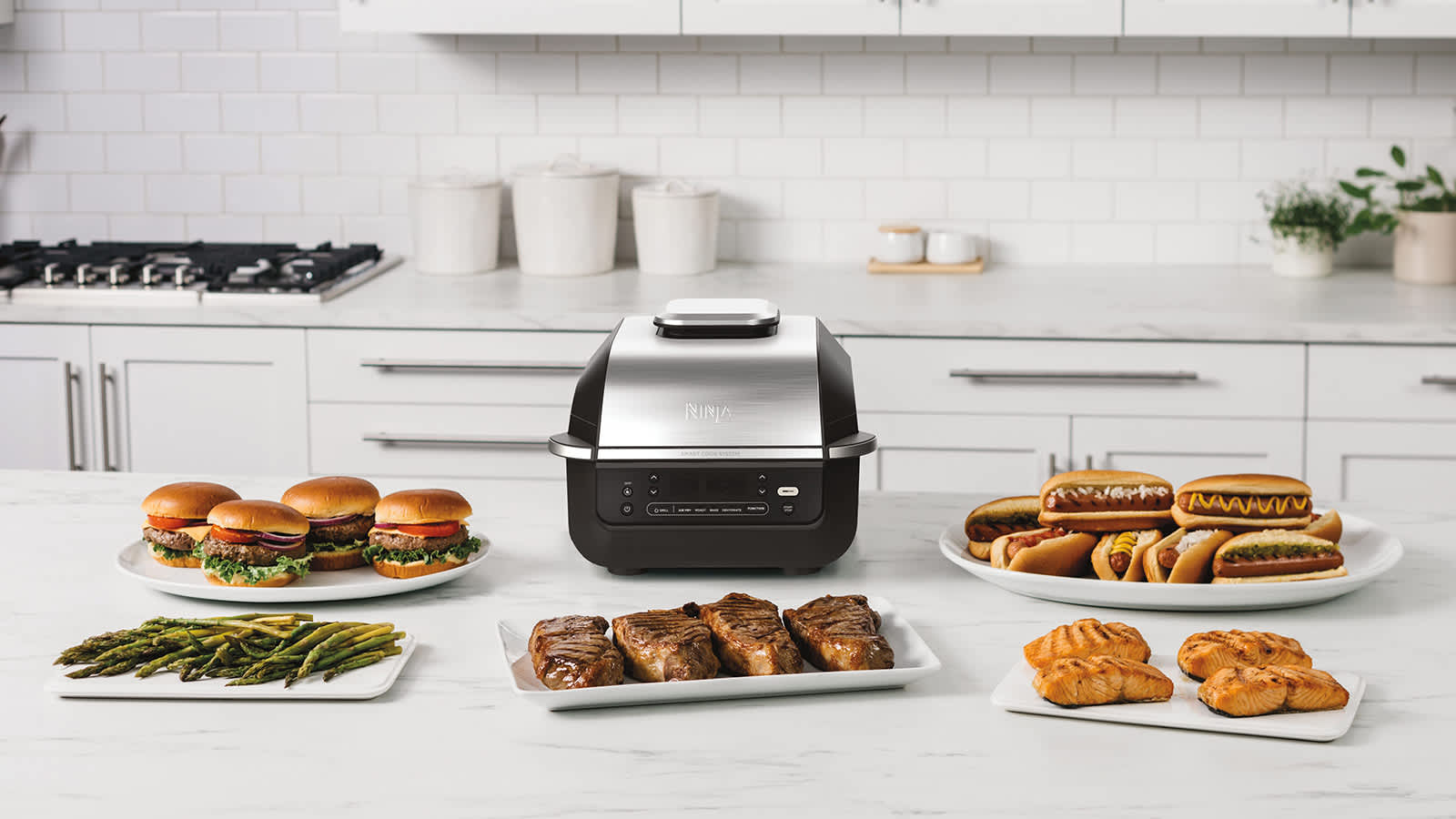 Airfryer et grill Ninja pos&eacute;s sur une table, entour&eacute;s de plusieurs assiettes de nourriture.
