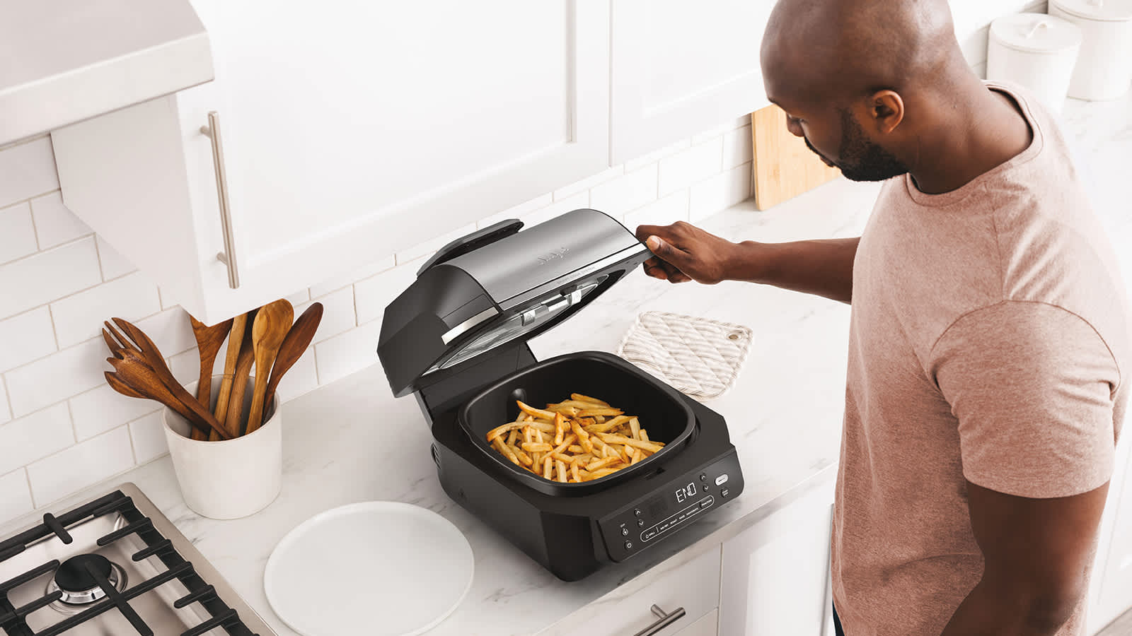 Personne cuisant des frites avec le grill et l&rsquo;Airfryer Ninja.