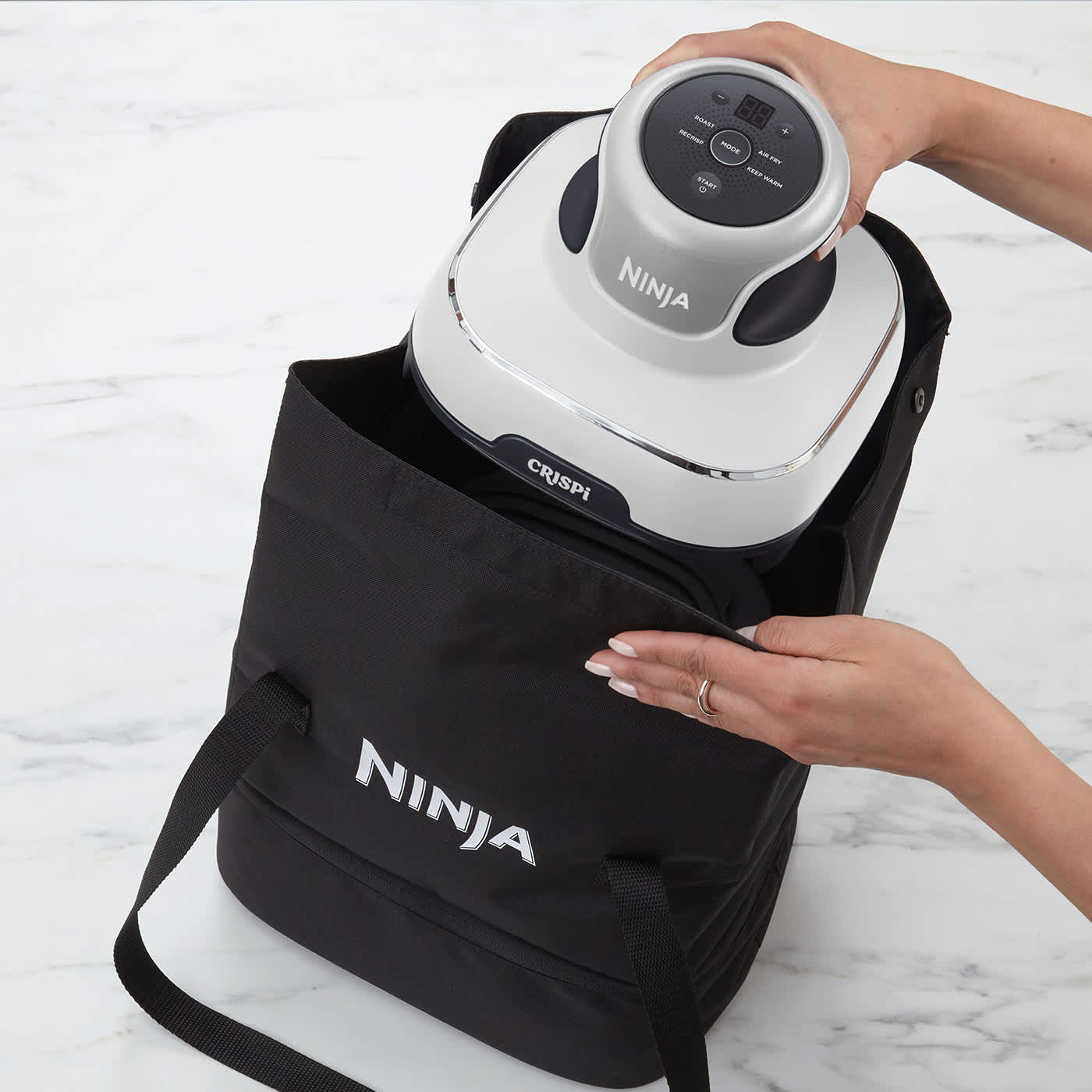 Personne pla&ccedil;ant le Ninja Crispi dans un sac de transport.