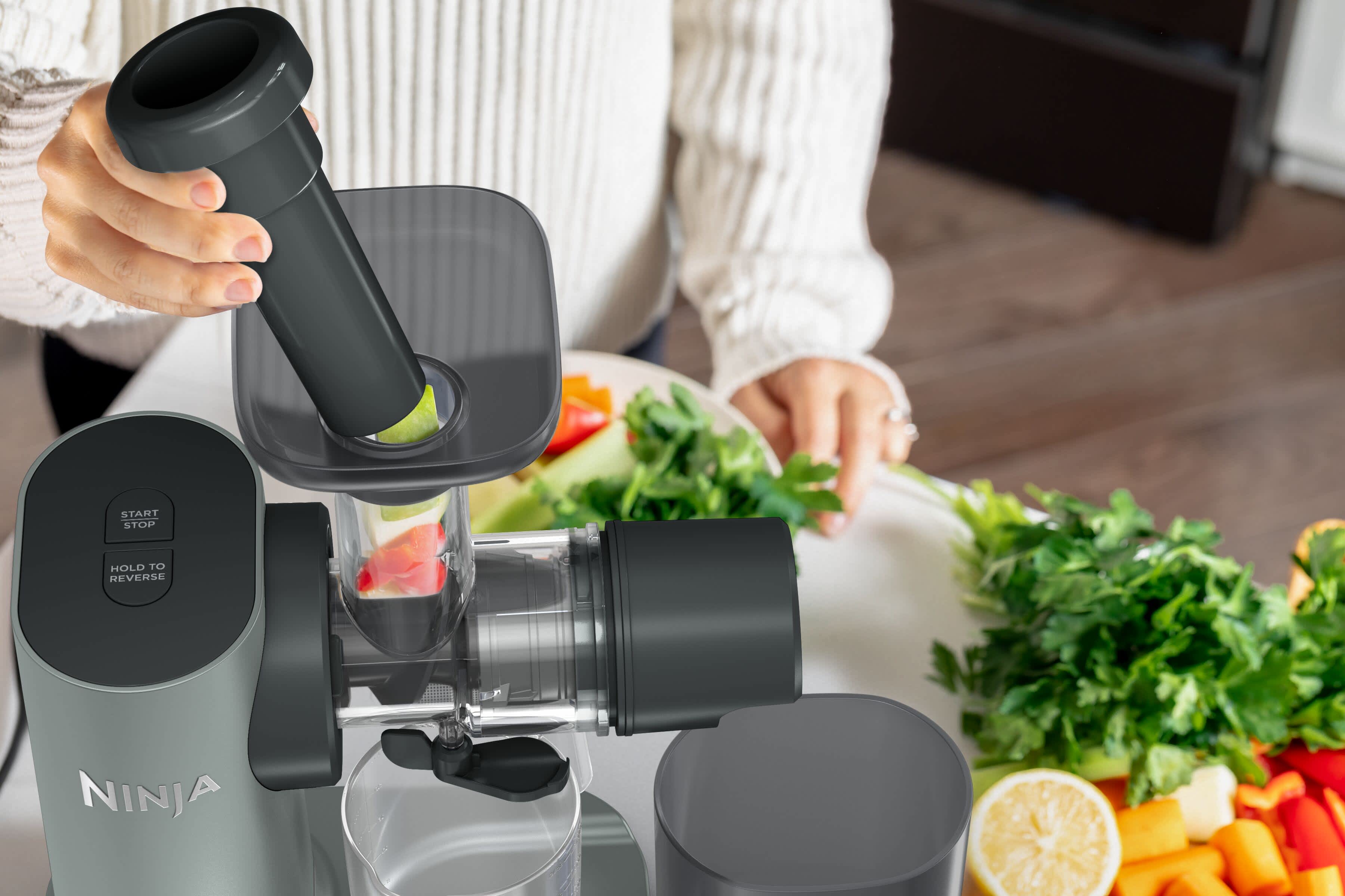 Airfryer avec tiroir ouvert contenant du poisson, un p&egrave;re servant une assiette &agrave; son fils, avec des plats de l&eacute;gumes sur la table.