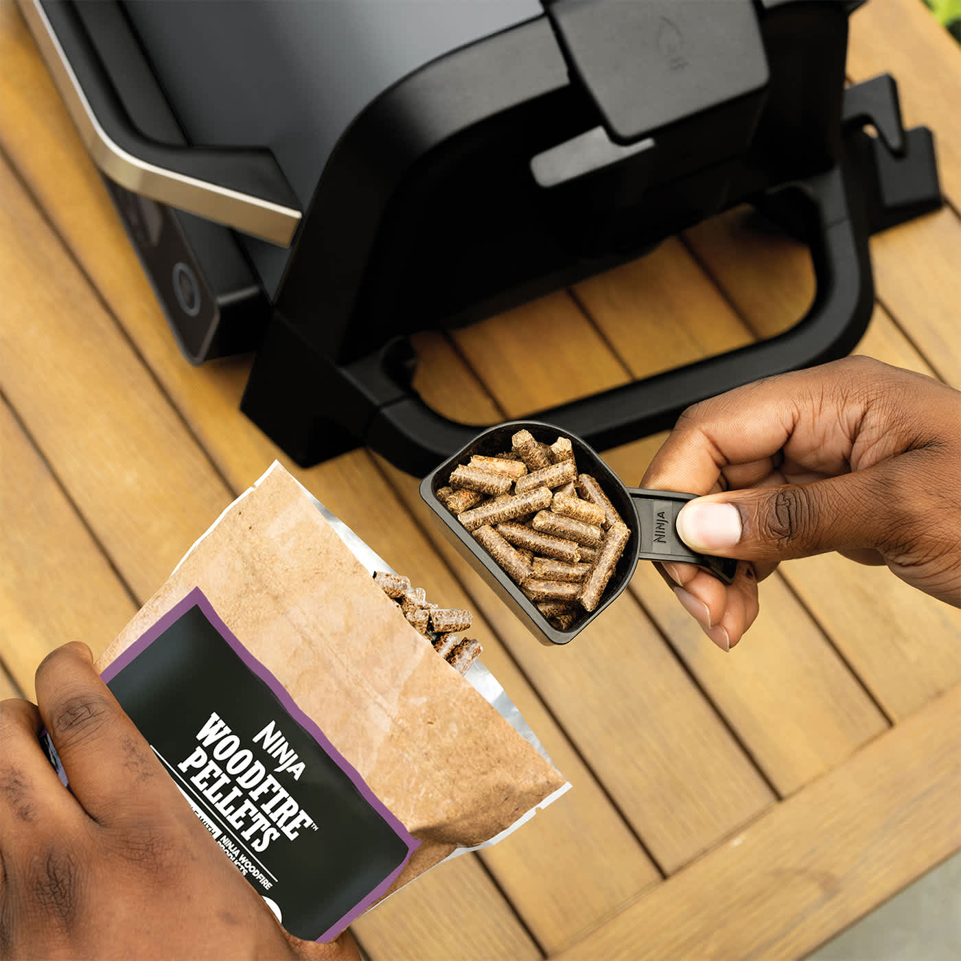 Personne ajoutant des pellets dans le barbecue Ninja.