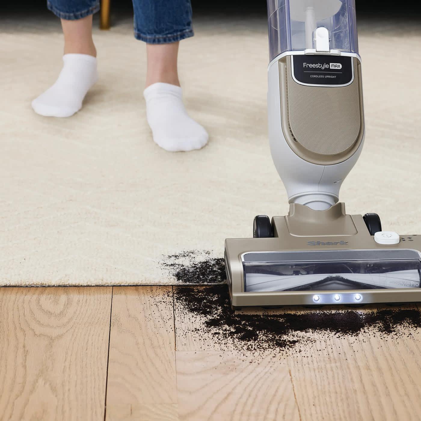 Personne aspirant la salet&eacute; d'un tapis et du sol dur avec l'aspirateur sans fil Ninja.