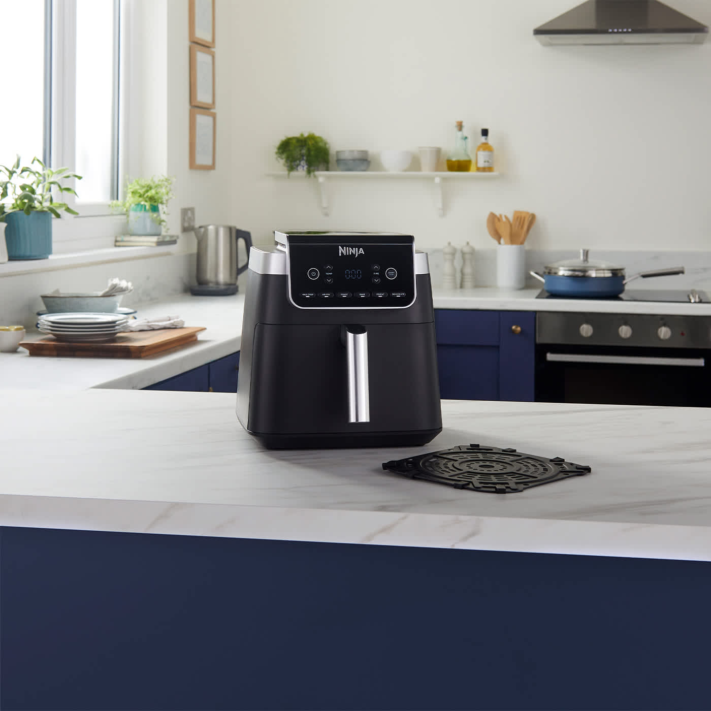 Ninja Air Fryer auf der K&uuml;chenzeile, darum herum verschiedene zubereitete Gerichte.