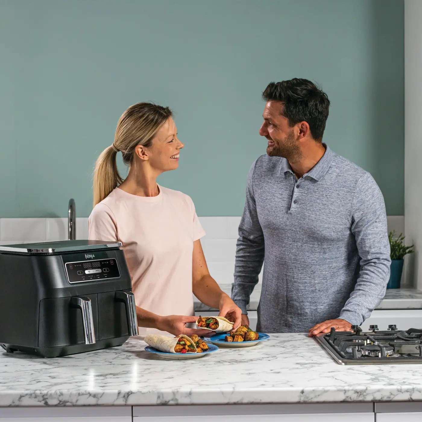 Zwei Personen bereiten gemeinsam Essen vor dem Dual-Zone Ninja Air Fryer zu.