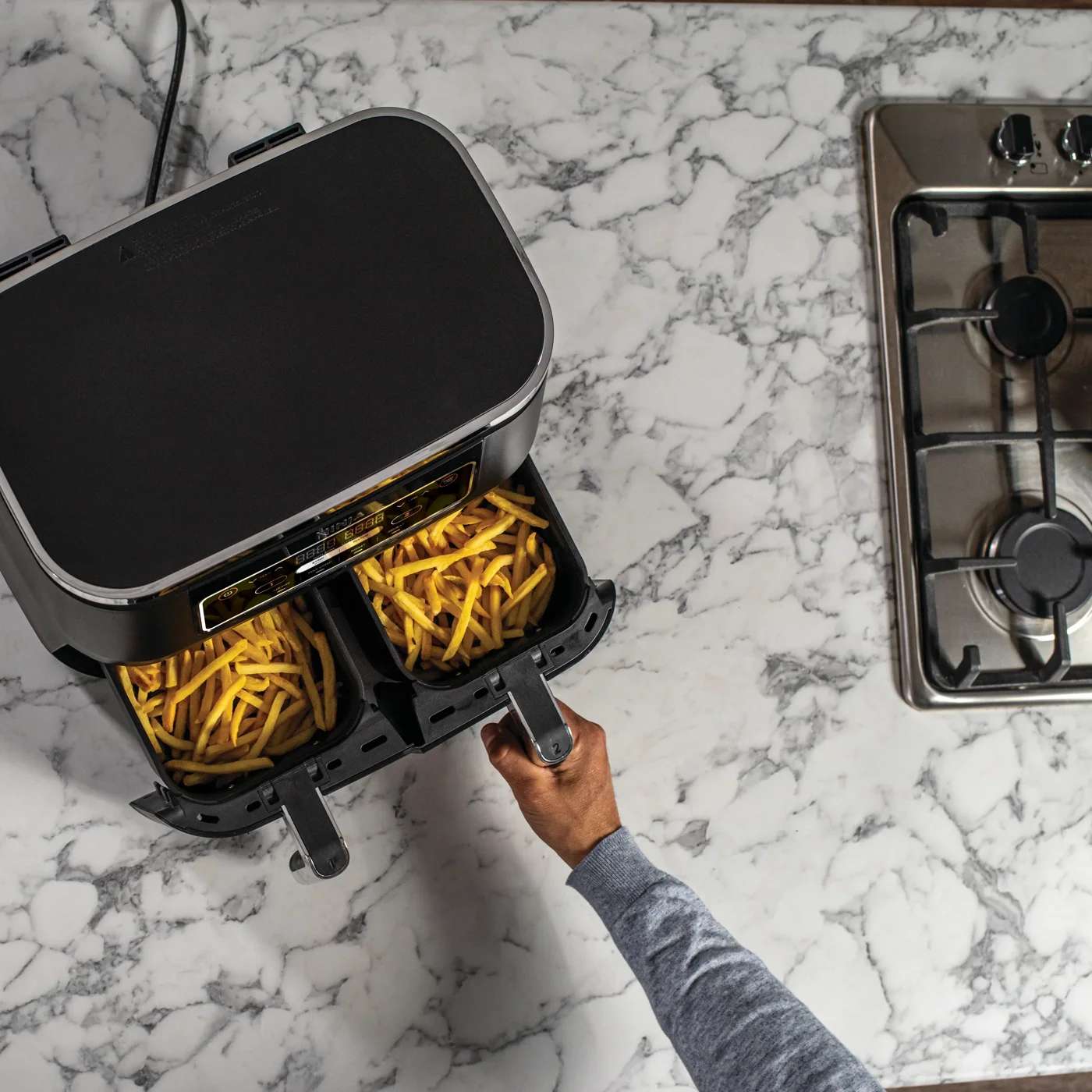 Dual-Zone Ninja Air Fryer mit offener Schublade, darin knusprige Pommes.