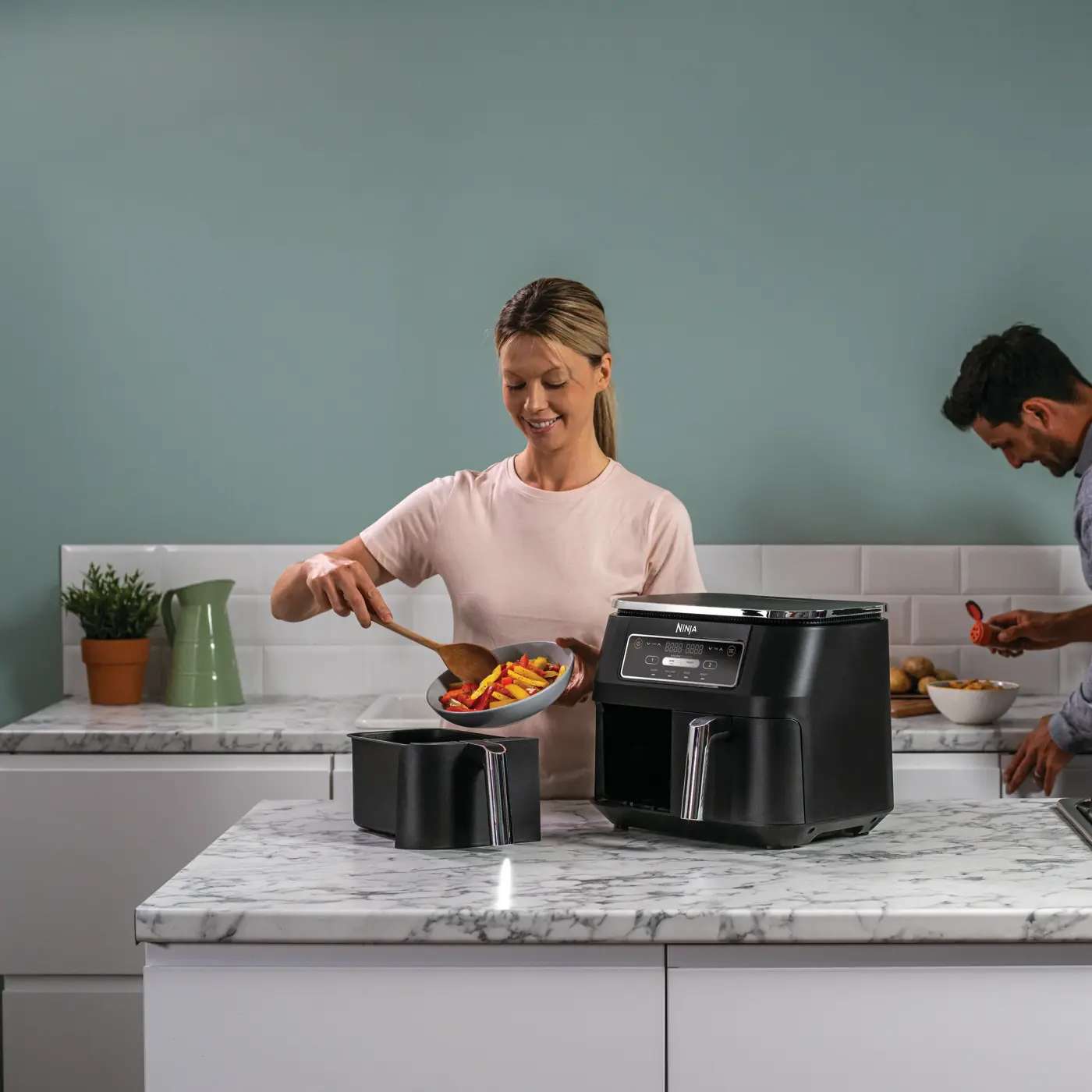 Person nimmt frisch zubereitetes Essen aus dem Dual-Zone Ninja Air Fryer.