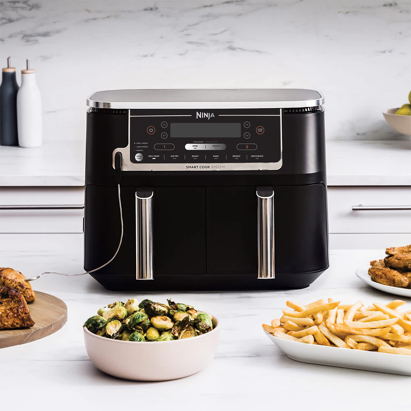 Ninja Air Fryer umgeben von verschiedenen fertigen Gerichten.
