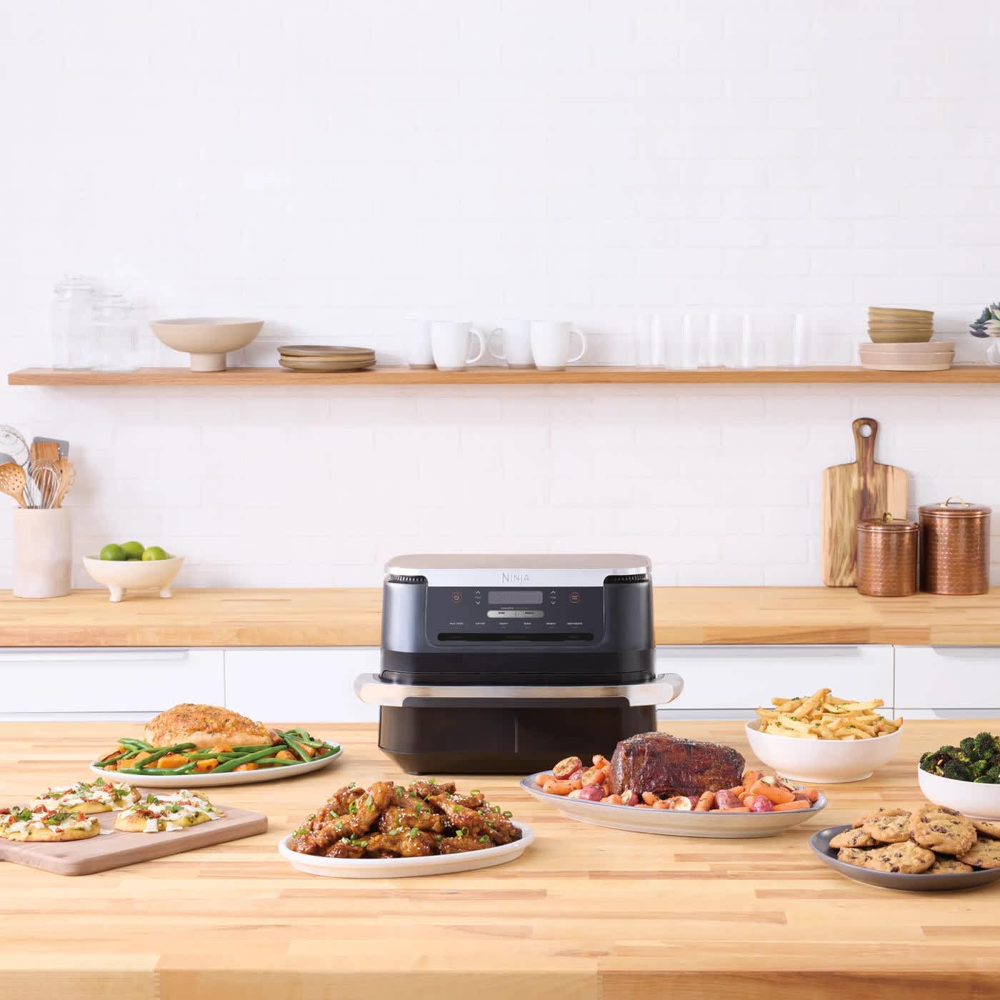 Ninja Air-Fryer steht auf der K&uuml;chenzeile mit Gerichten drum herum.