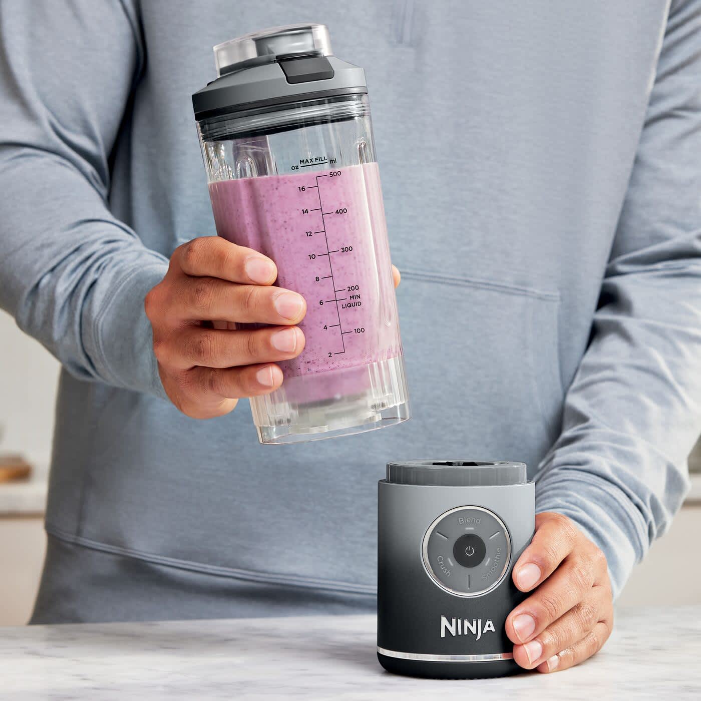 Personne fixant un gobelet sur le blender portable Ninja.