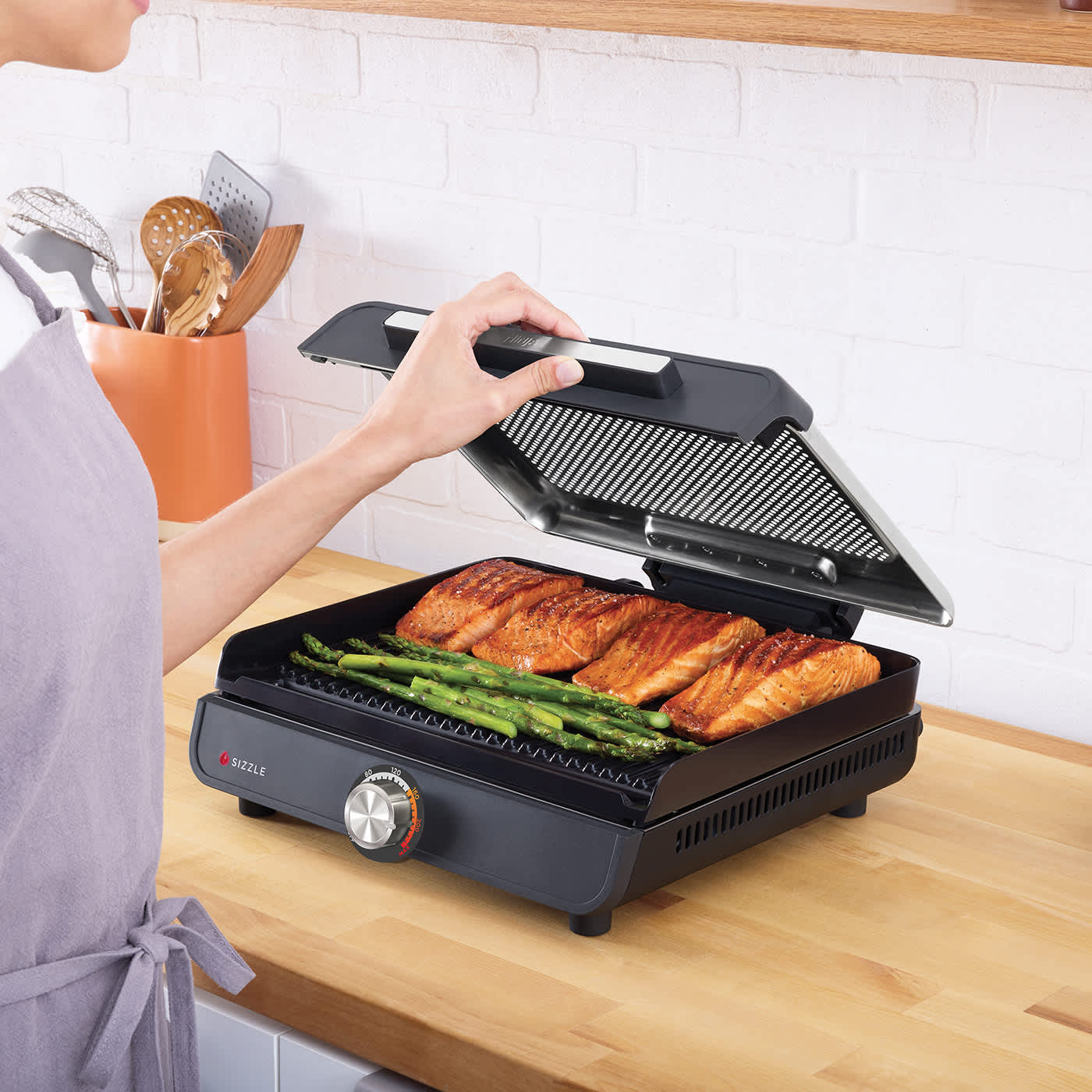 Person nimmt den Deckel beim Ninja Sizzle Grillplatte und Plancha ab.