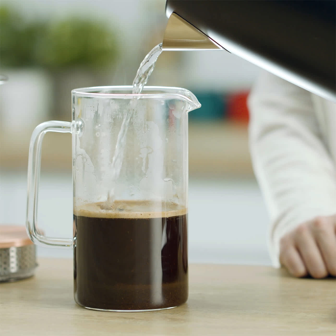 Person gie&szlig;t hei&szlig;es Wasser aus dem Ninja Wasserkocher KT200EU in ein Beh&auml;lter, um Kaffee aufzugie&szlig;en.