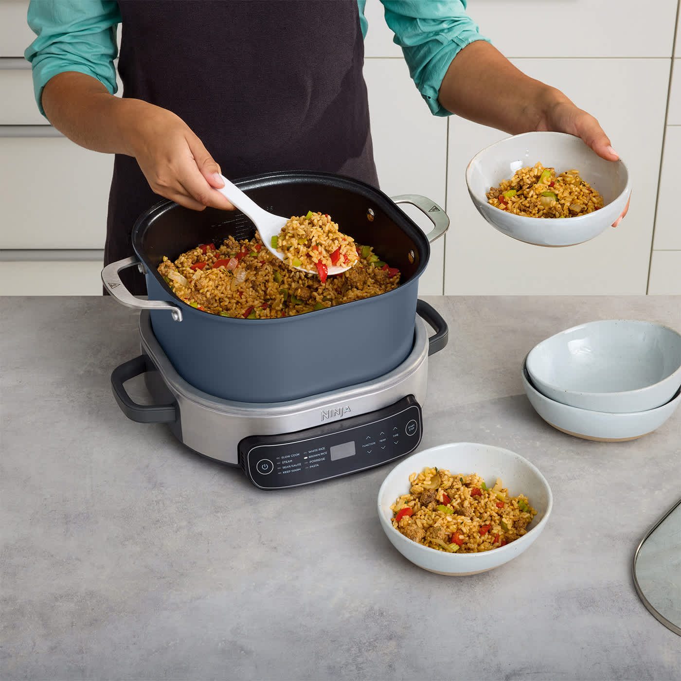 Foodi PossibleCooker in Nachtblau beim Servieren von frisch gekochtem Reis direkt aus dem antihaftbeschichteten 6-Liter-Topf.