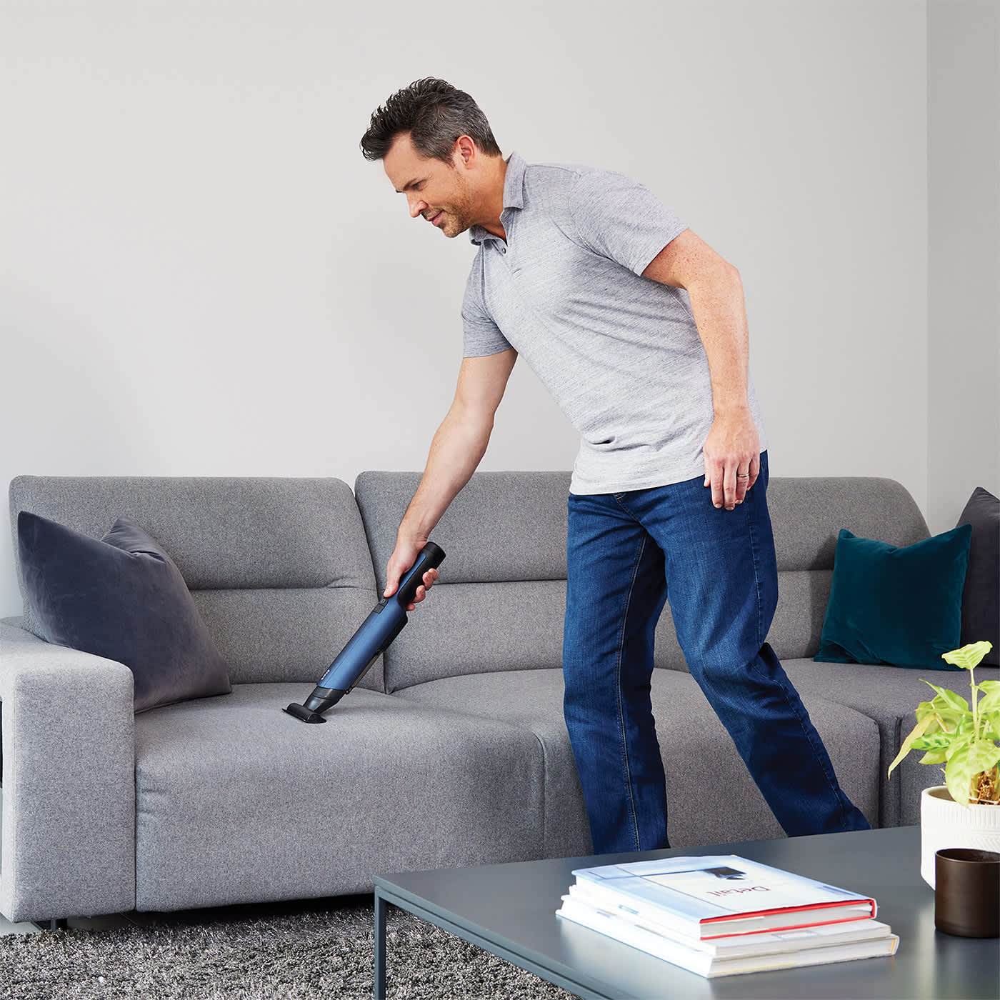 Eine Person saugt Sofa mit dem Shark Akku-Handstaubsauger