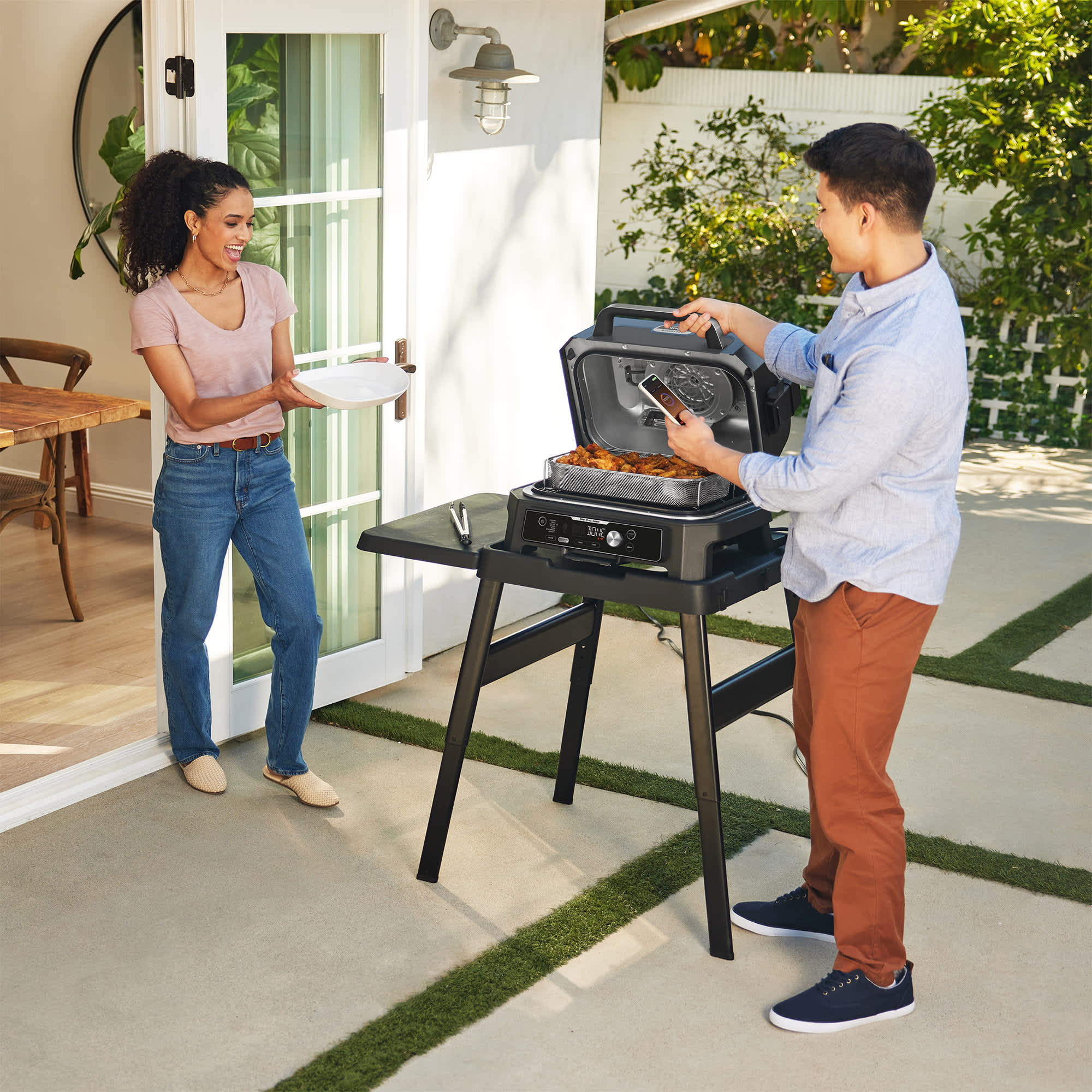 Mann und Frau auf der Terasse mit Grill