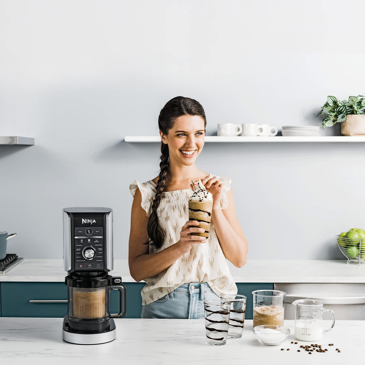 Immagine di una donna che beve un frappè preparato con la gelatiera Ninja CREAMi Deluxe