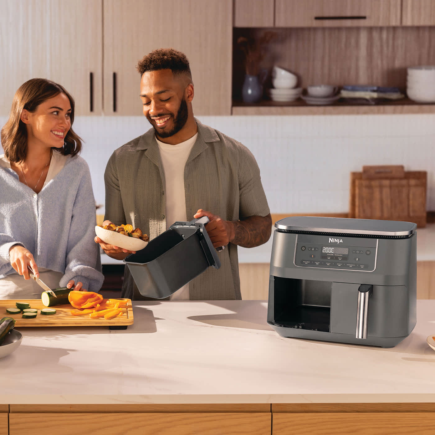 Friggitrice ad aria Ninja Dual Zone da 7,6 L con due ragazzi che preparano del cibo in cucina