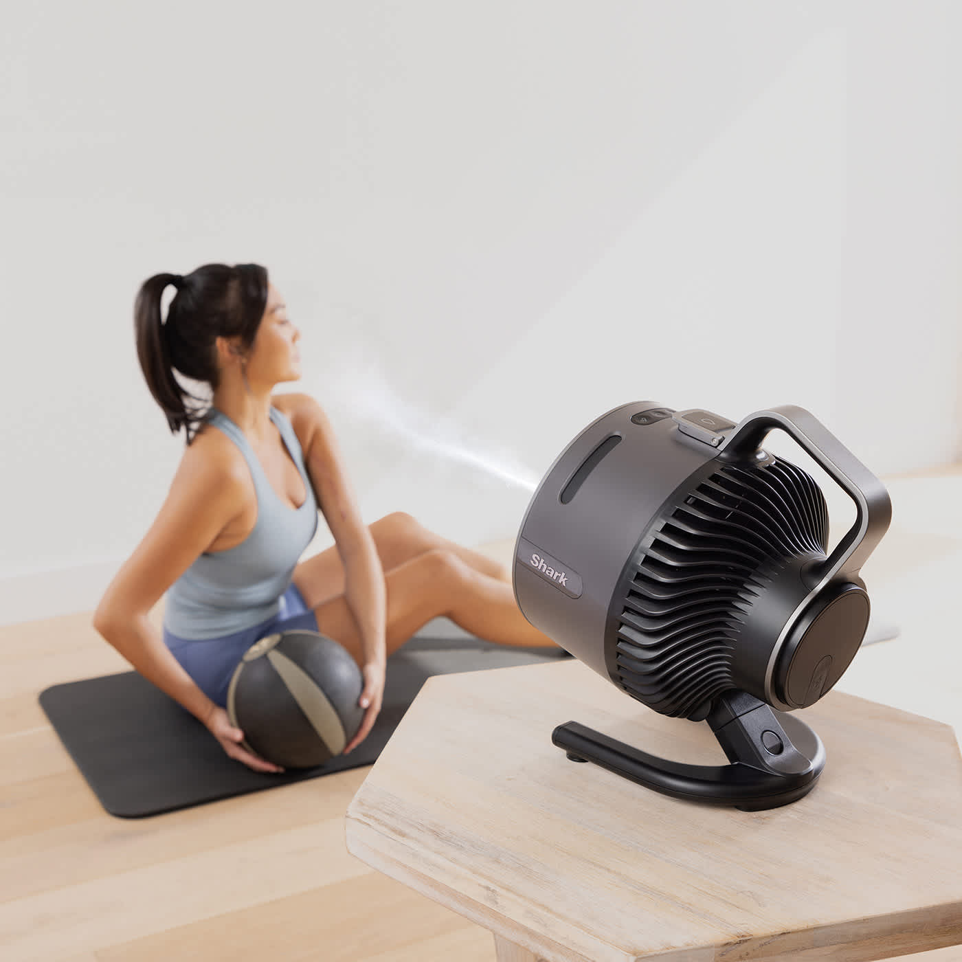 Immagine di una donna che fa yoga con il ventilatore Shark che la rinfresca