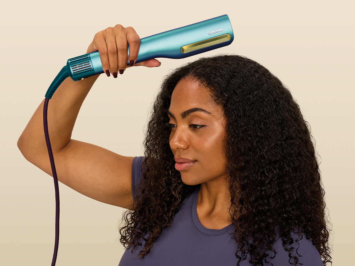 Ragazza che si asciuga le radici dei capelli con la piastra Shark SilkiPro