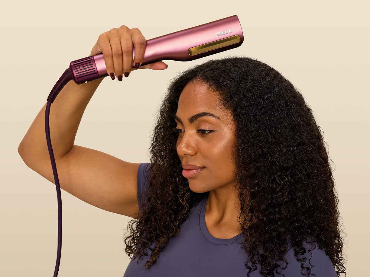 Ragazza che si asciuga le radici dei capelli con la piastra Shark SilkiPro