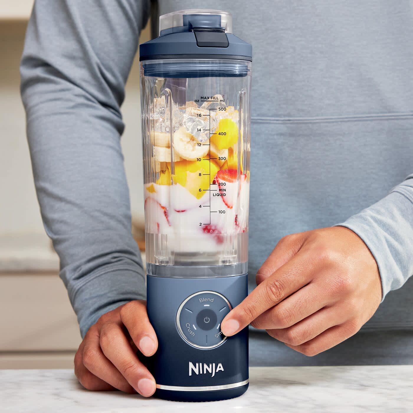 Uomo che preme un pulsante del frullatore portatile Ninja Blast Max