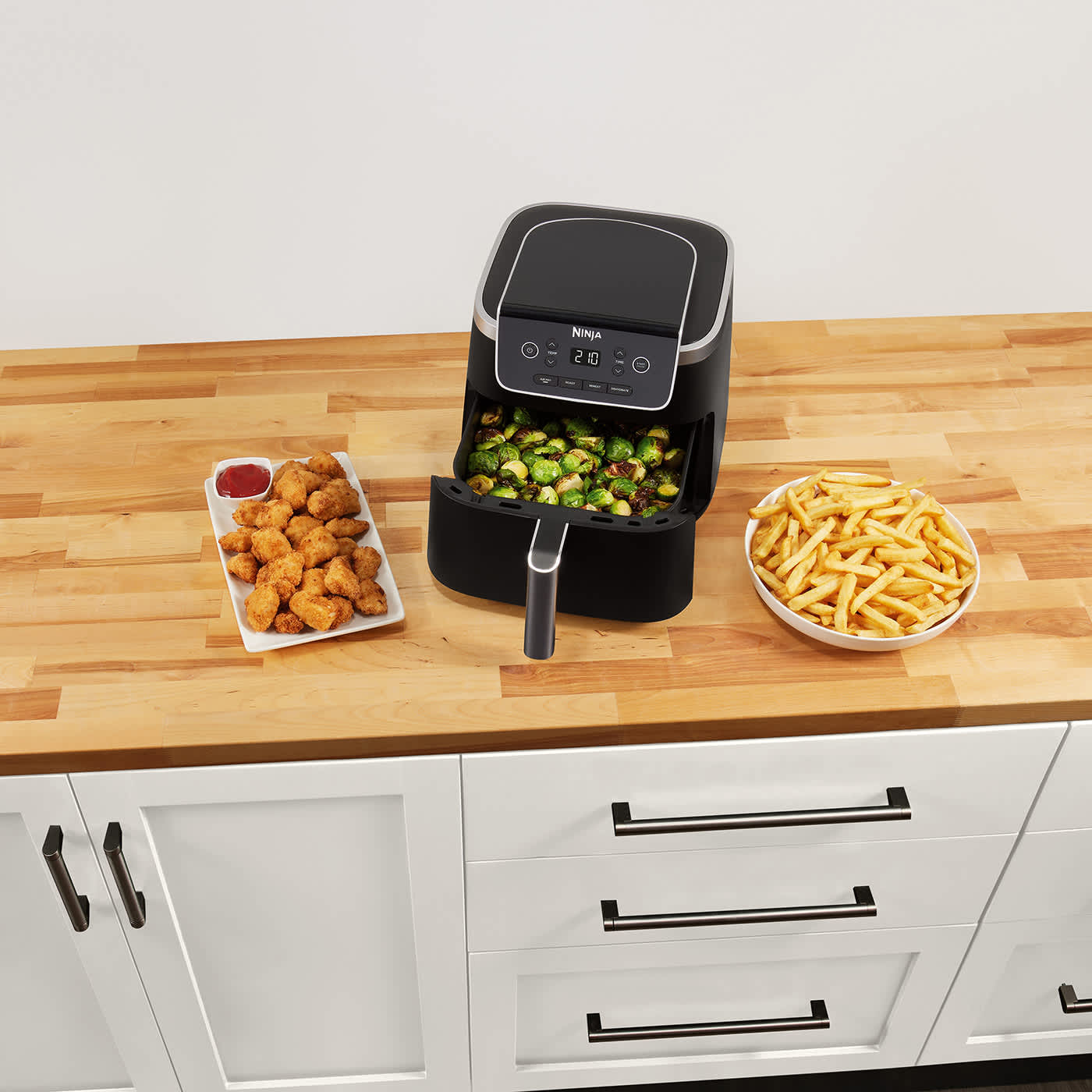Air Fryer Ninja AF140EU na stole z upieczonymi obok posiłkami