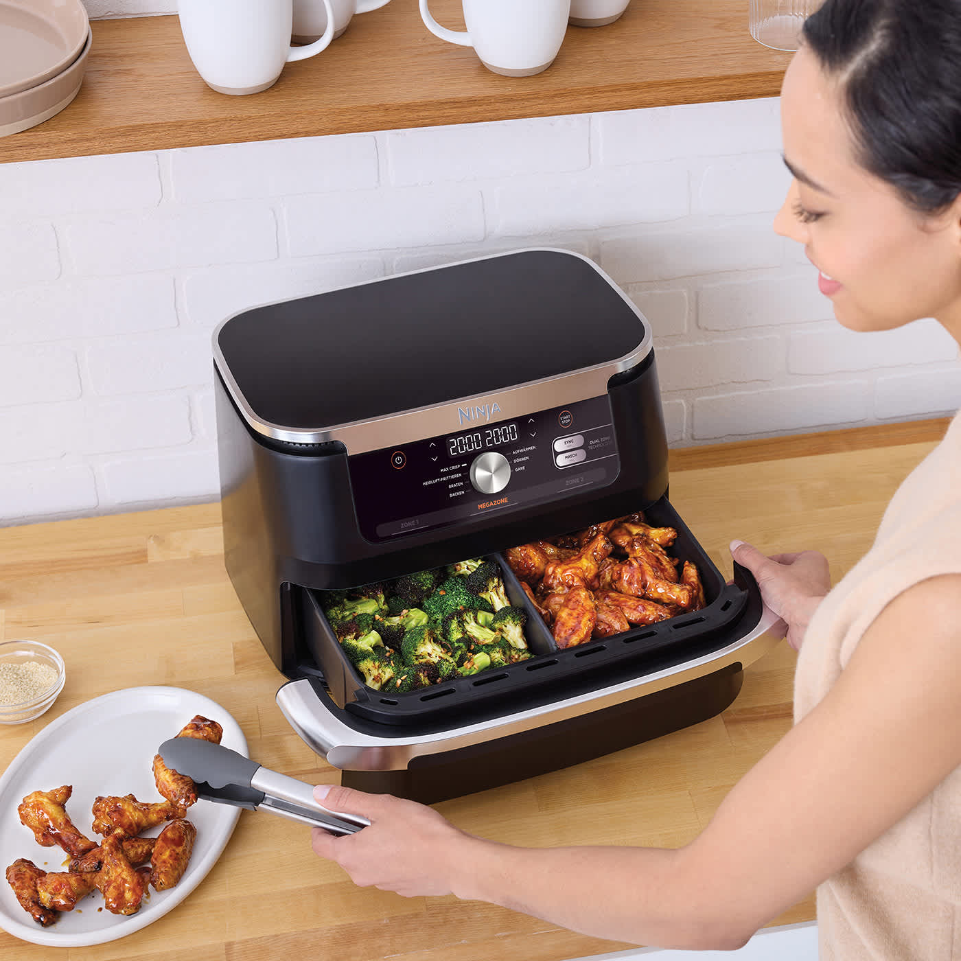 Kobieta wyjmująca gotowe potrawy z air fryera Ninja Foodi FlexDrawer 10,4 l AF500EU
