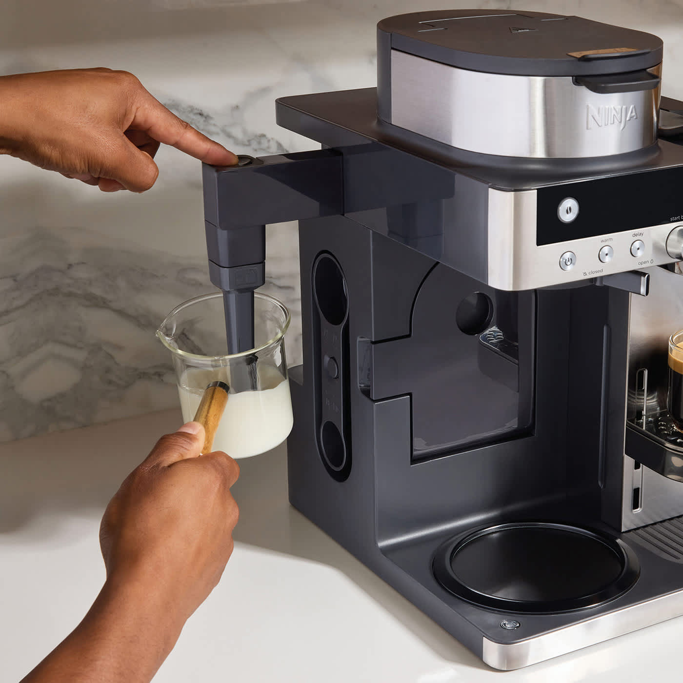 Osoba spenia mleko w ekspresie przelewowym i kapsułkowym Ninja Prestige DualBrew System CFN803EU