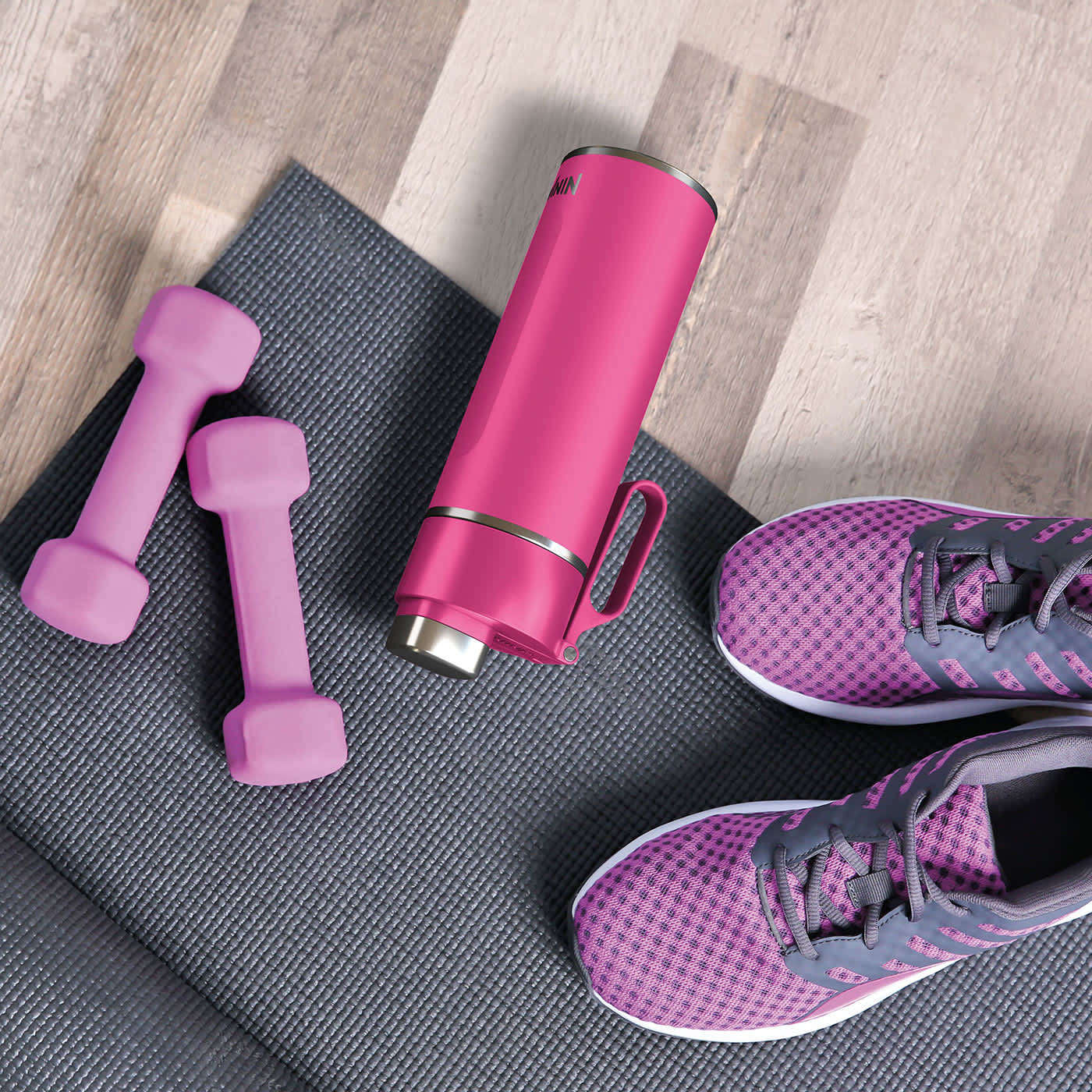 Bidon Ninja Thirsti DW1801EUUK leżący na macie do ćwiczeń na siłowni wśr&oacute;d hantli i but&oacute;w sportowych