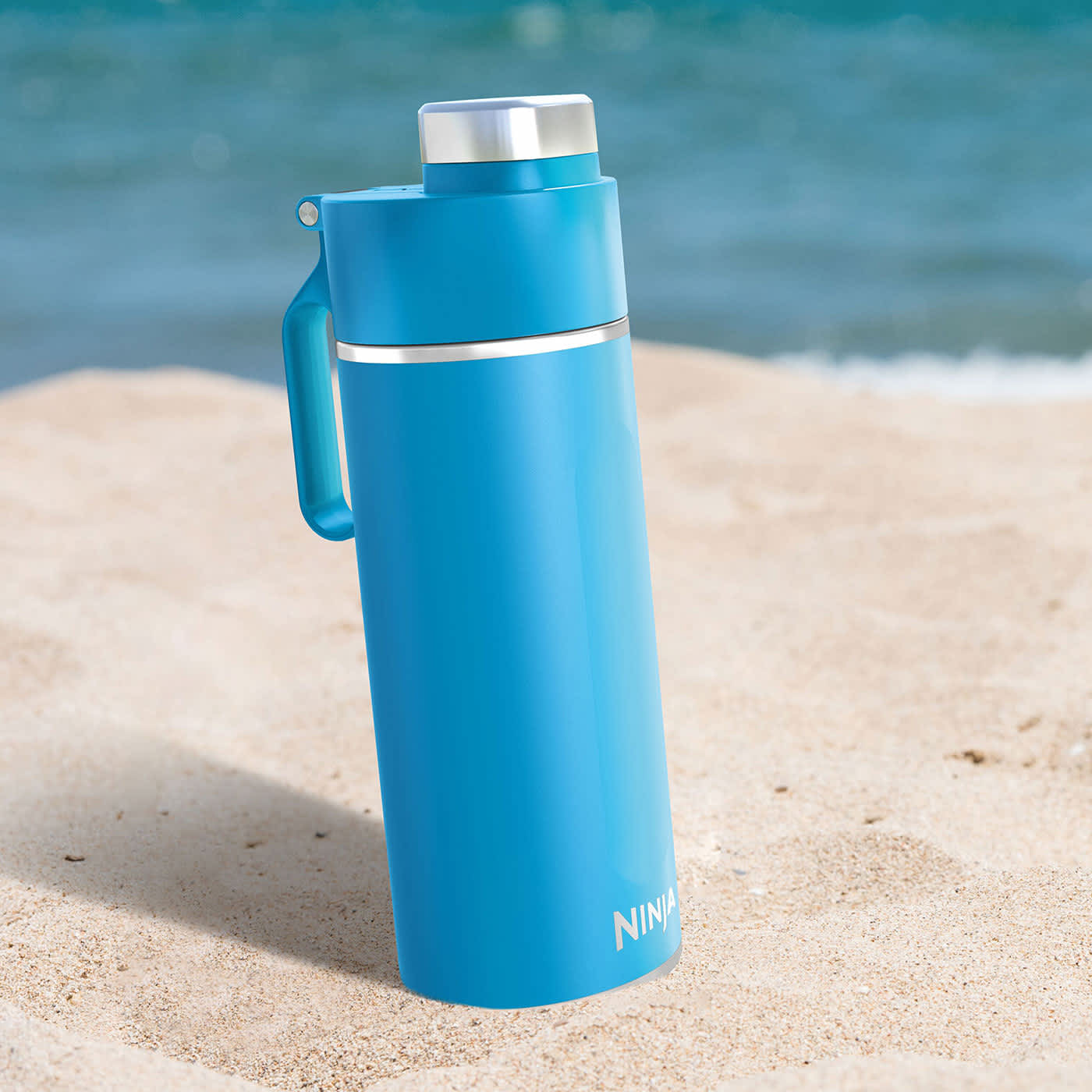 Bidon Ninja Thirsti DW2401EUUK stojący na gorącym piasku na plaży