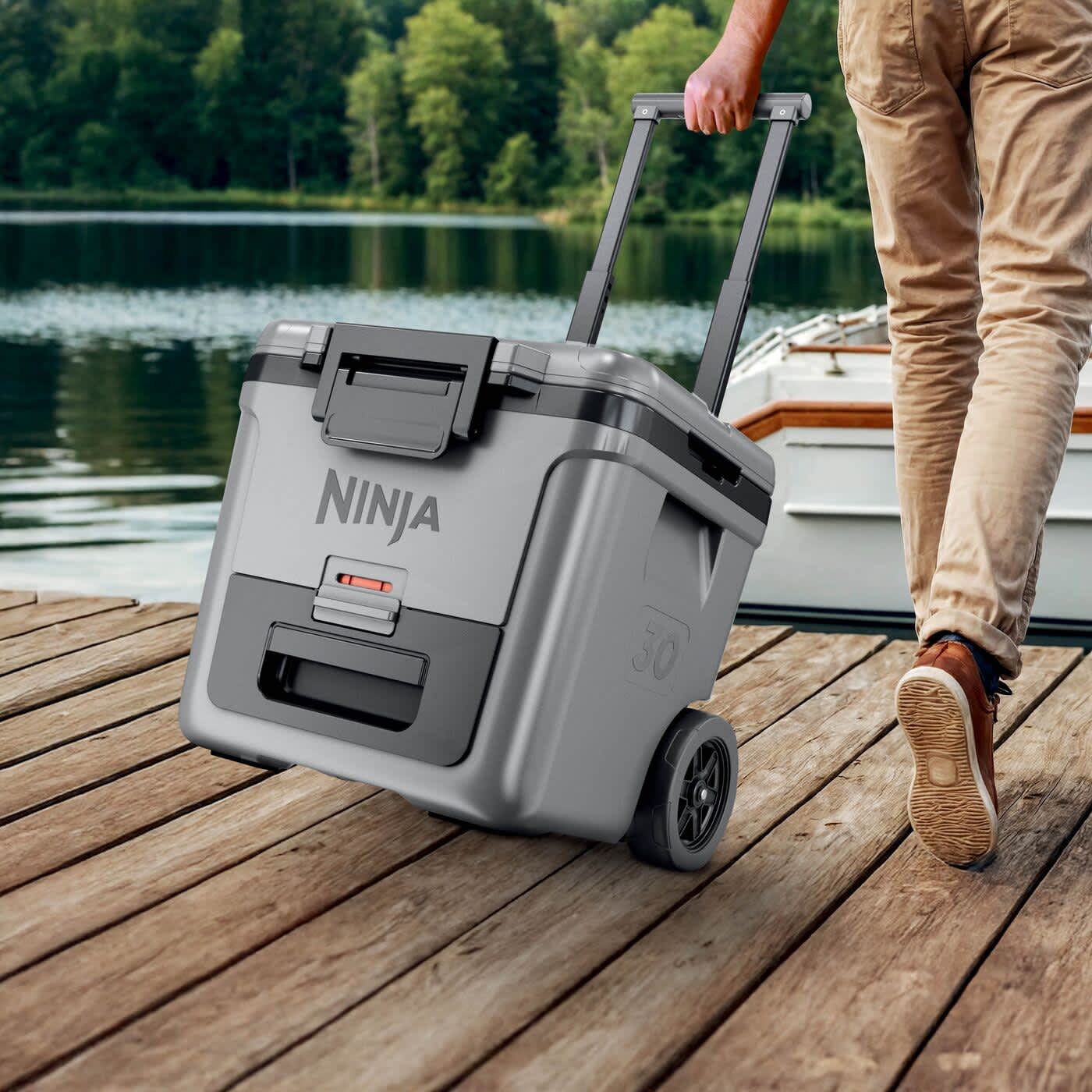 Mężczyzna ciągnie za sobą z lod&oacute;wkę na k&oacute;łkach ze strefą suchą Ninja FrostVault 28L FB230EUGY