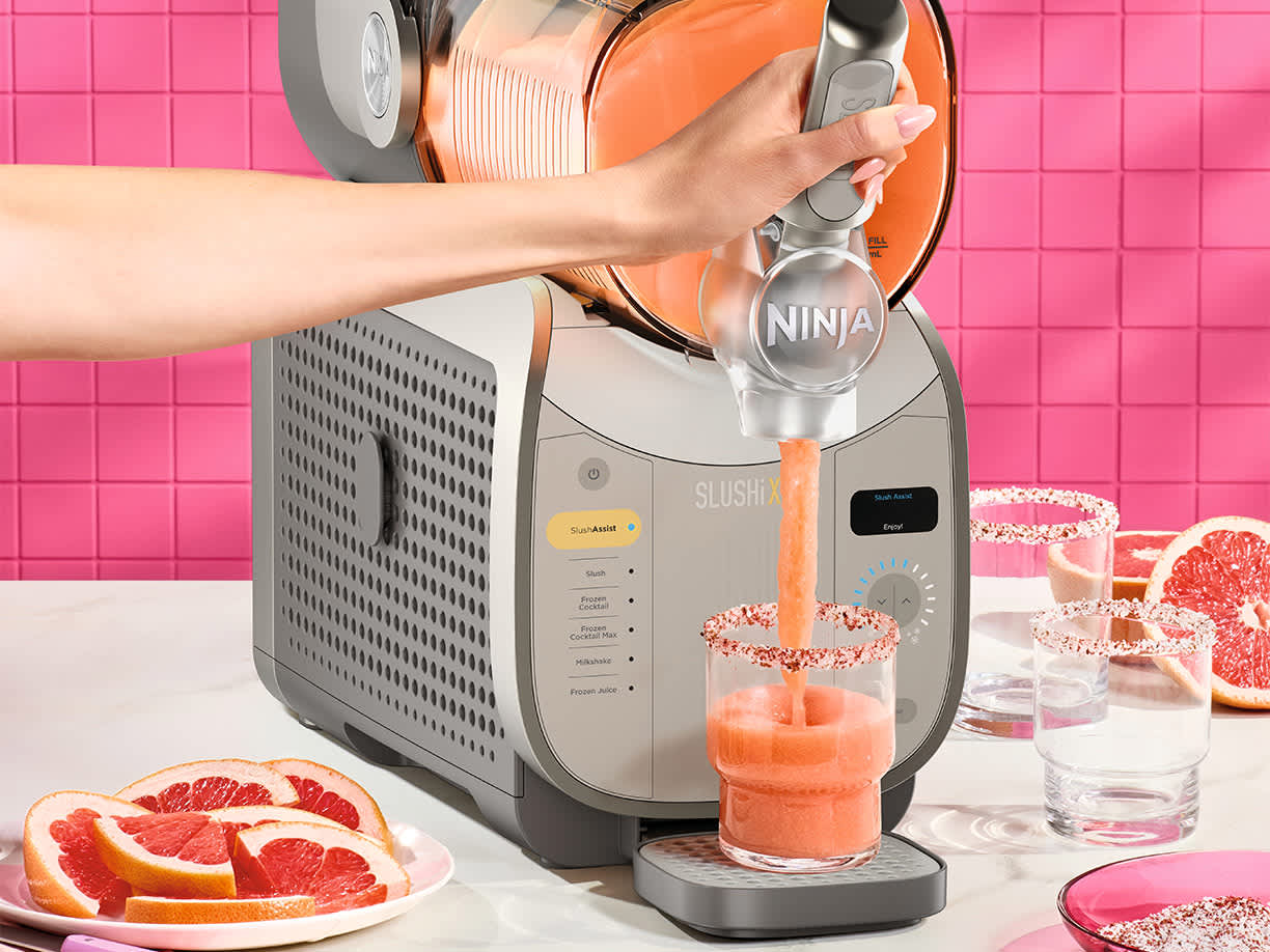 Osoba nalewa do szklanki gotowe slushy uprzednio zmrożone w maszynce do mrożonych napoj&oacute;w i slushy Ninja Slushi XL FS601EU