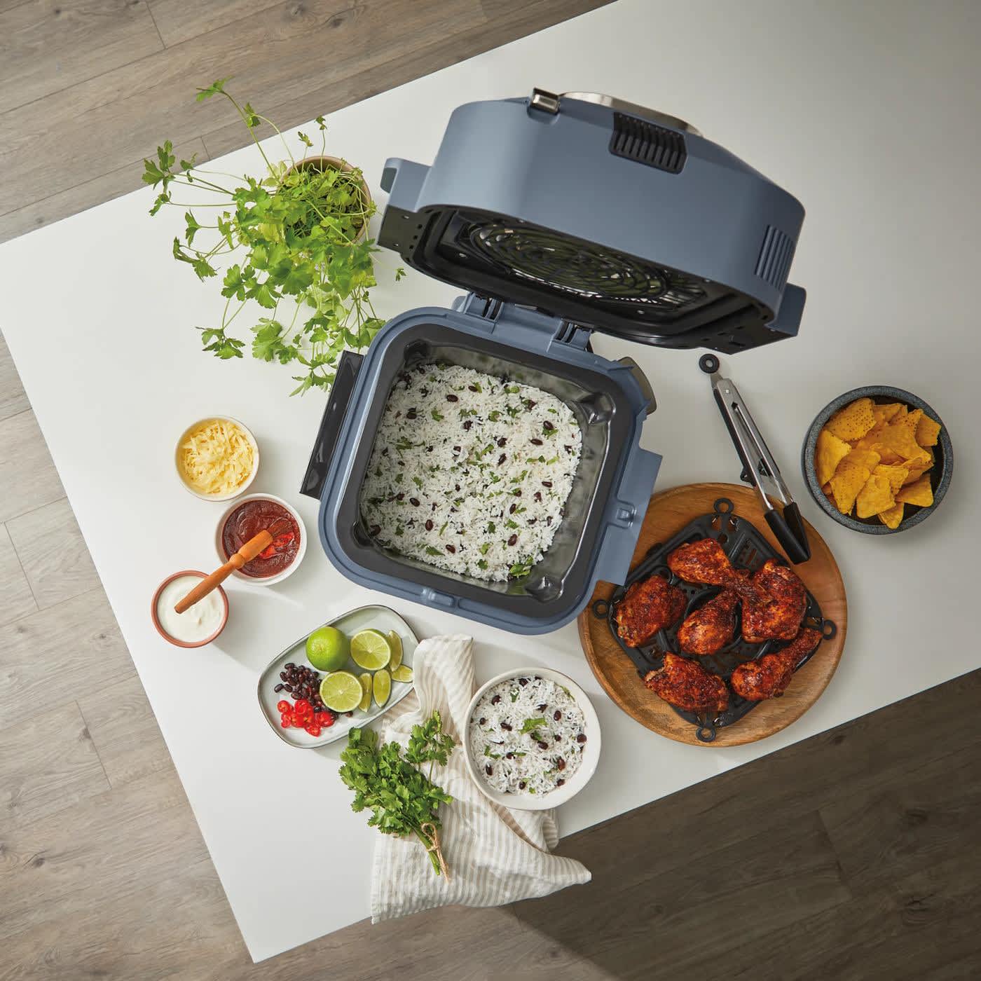 Multicooker Ninja Speedi ON500EUCYD stojący na blacie kuchennym z wieloma posiłkami obok, widziany od g&oacute;ry