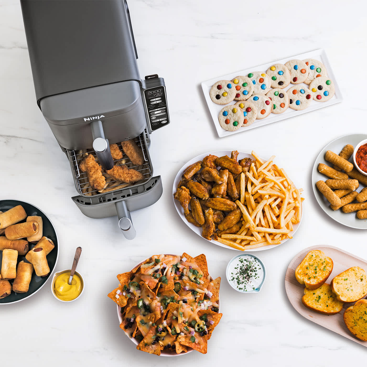 Ninja air fryer entour&eacute; par des plats de nourriture